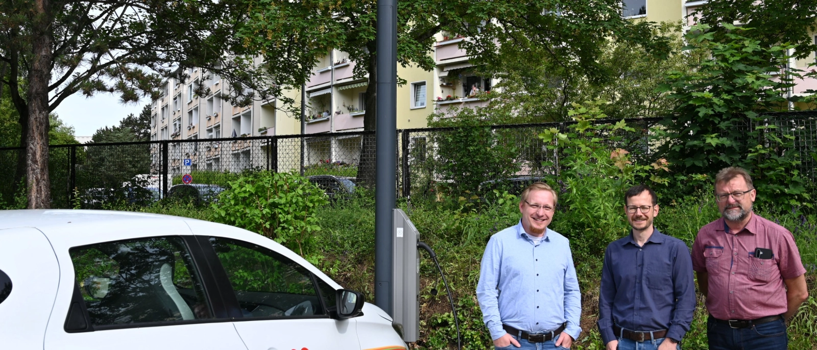 Frank Burkert, Leiter der Tagespflege im AWO Wohnpark Lebenszeit, Andreas Well von den Stadtwerken Energie Jena-Pößneck und Heiko Hirte, Projektmitarbeiter im Projekt JenErgieReal neben dem neuen Laternenlader auf dem Parkplatz der Tagespflege in der Rudolf-Breitscheid-Straße in Jena-Lobeda. 