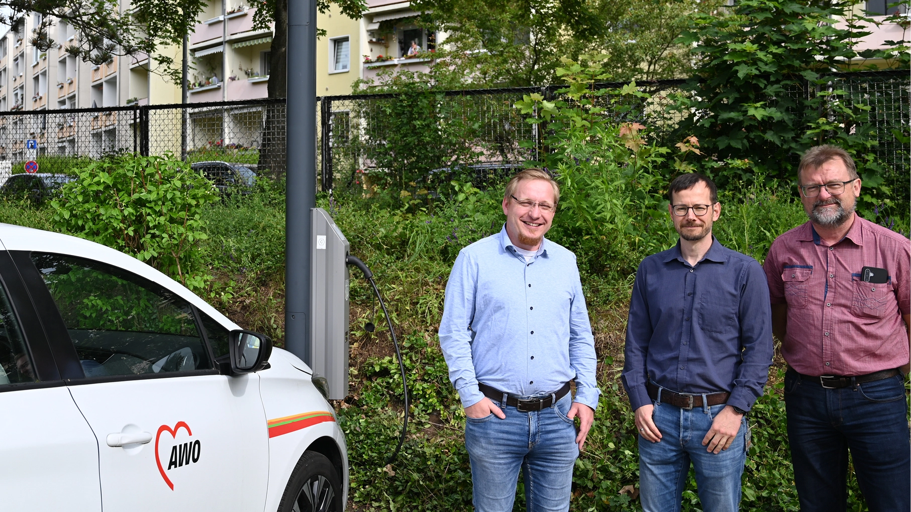 Frank Burkert, Leiter der Tagespflege im AWO Wohnpark Lebenszeit, Andreas Well von den Stadtwerken Energie Jena-Pößneck und Heiko Hirte, Projektmitarbeiter im Projekt JenErgieReal neben dem neuen Laternenlader auf dem Parkplatz der Tagespflege in der Rudolf-Breitscheid-Straße in Jena-Lobeda. 