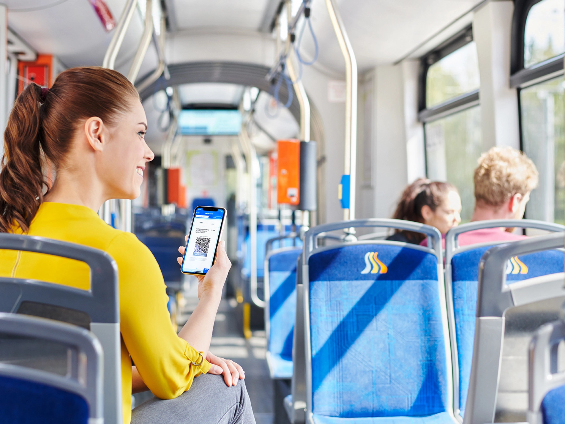 Eine Frau sitzt mit ihrem Handy in der Straßenbahn.