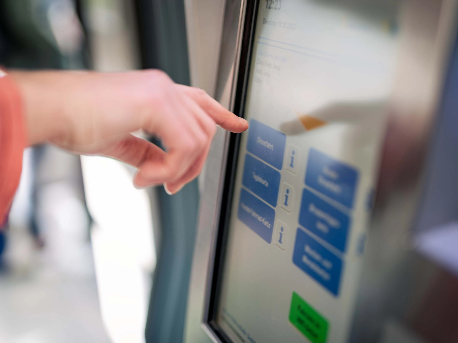 Eine Hand tippt auf das Display eines Fahrscheinautomaten im Fahrzeug.