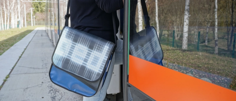 Eine Person steigt mit einer Umhängetasche in eine Straßenbahn ein.