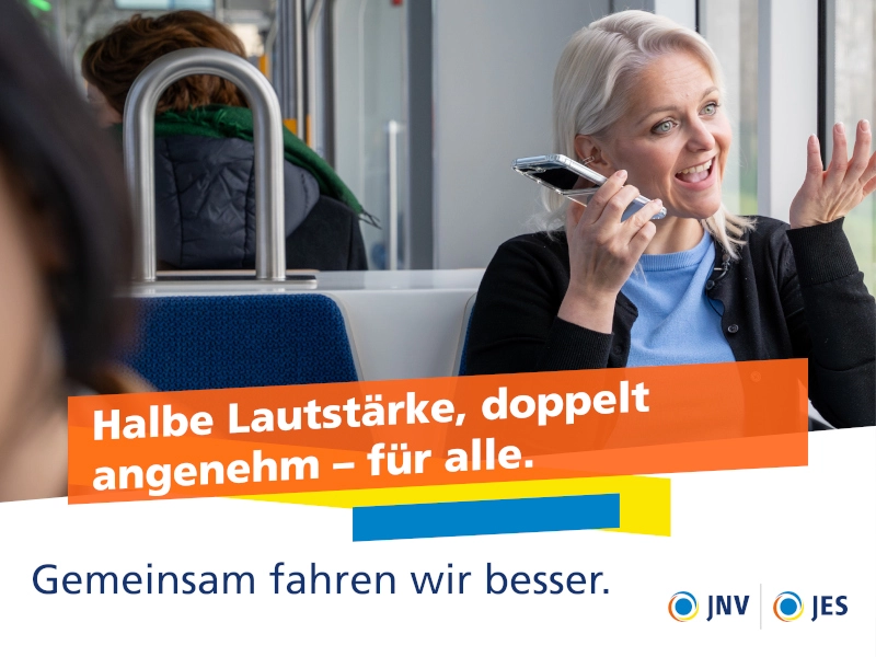 Eine blonde Frau sitzt telefonierend und gestikulierend in der Lichtbahn am Fenster.