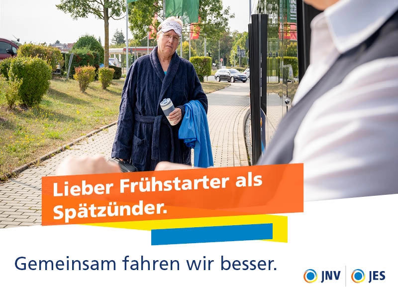 Eine Frau im Bademantel schlendert zum Bus, während die Fahrerin auf ihre Uhr zeigt.