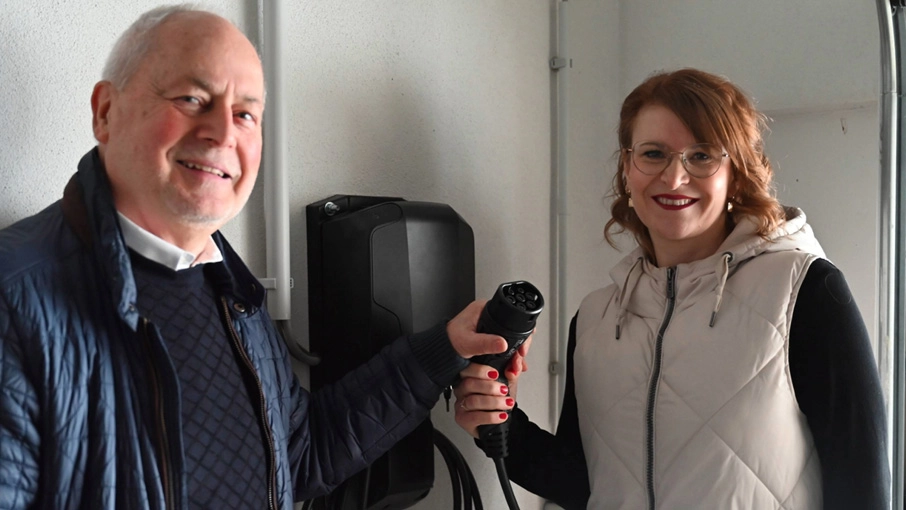 Hausverwalter und Mitarbeiterin der Stadtwerke an einer Ladesäule im Haus